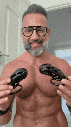 A man holds the KINK3D Cobra and Viper chastity cages, available at Clonezone